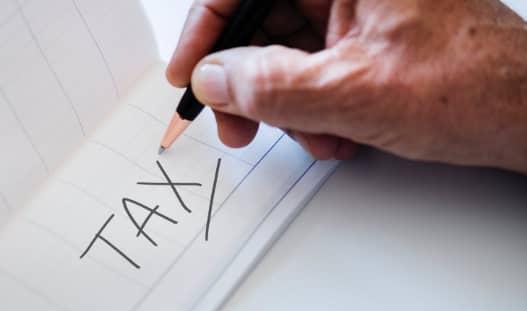 a person writing the word tax